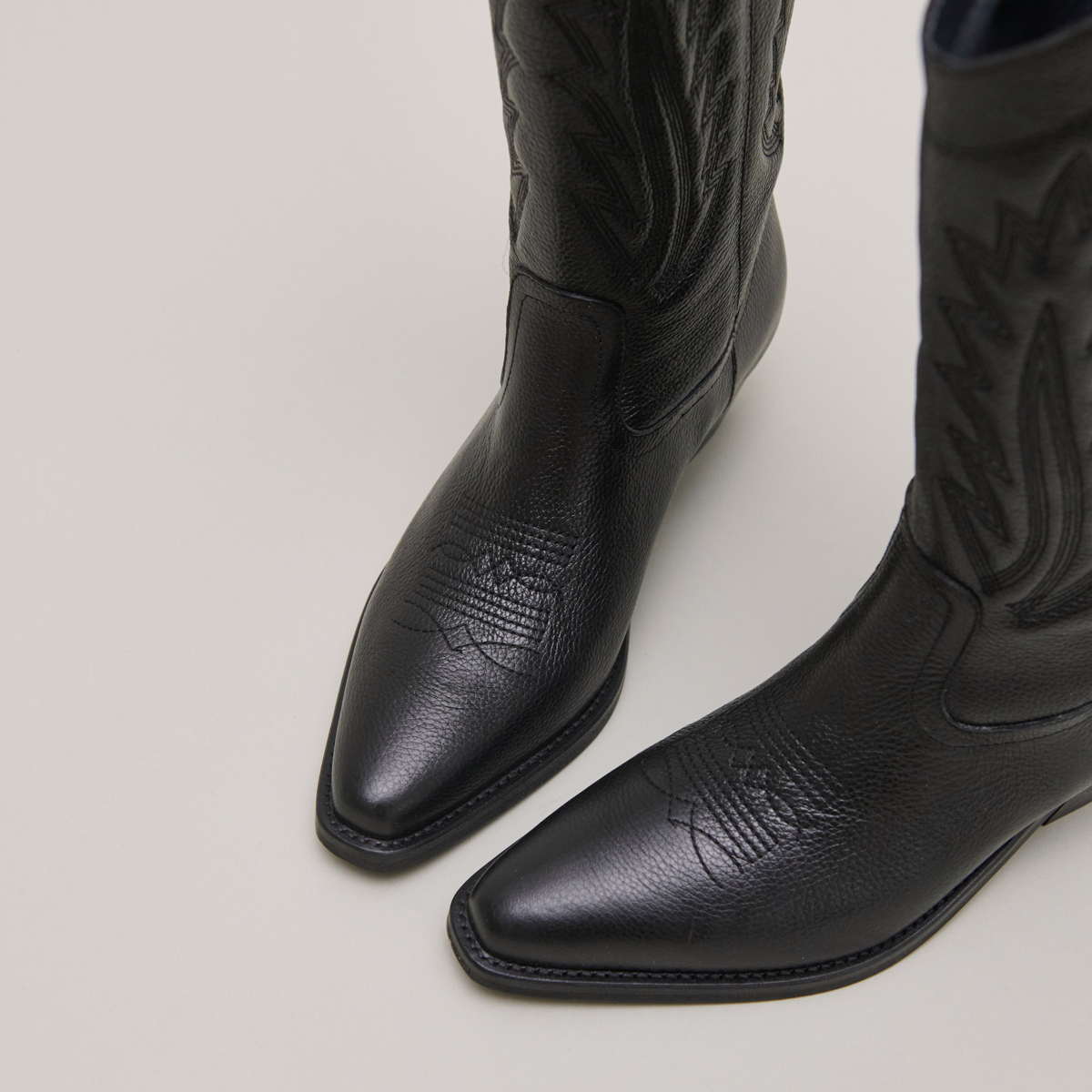 Pointed toe boots with exposed stitching in black grained leather | DELEA